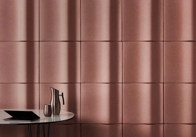 Interior design with a metallic pitcher and glass on a round table against a textured panel wall with geometric patterns and linear lighting.