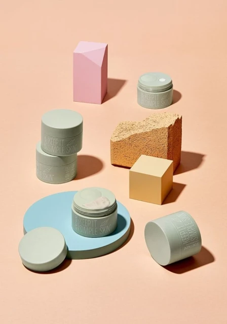 Still life studio shot of cosmetic jars and geometric shapes in pastel colors. Minimalist beauty product display on a peach background.