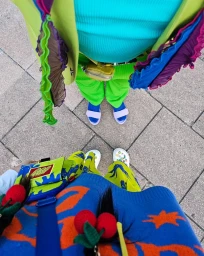 High-angle top-down shot of two people standing on a tiled stone pavement wearing colorful patterned outfits and bright accessories.