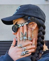 Close-up profile of a woman wearing a black baseball cap, sunglasses, and multiple statement silver rings by Tara Chandra in Sydney
