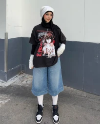 Content creator Tuba Dagli in Sydney wearing a black graphic t-shirt, blue denim shorts, white leg warmers, and sneakers outdoors