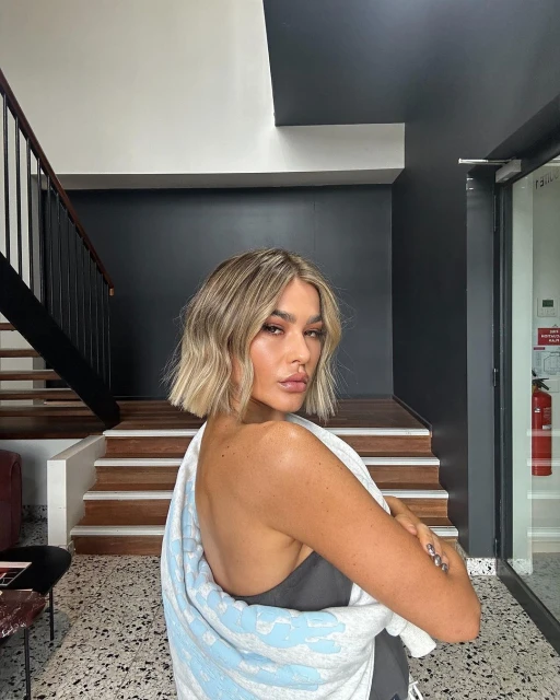 Blonde woman with towel posing indoors, stairs and natural light, beauty and fashion concept, shot in natural lighting.