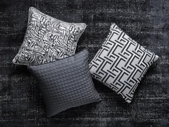 Three patterned cushions arranged diagonally on a dark textured fabric surface