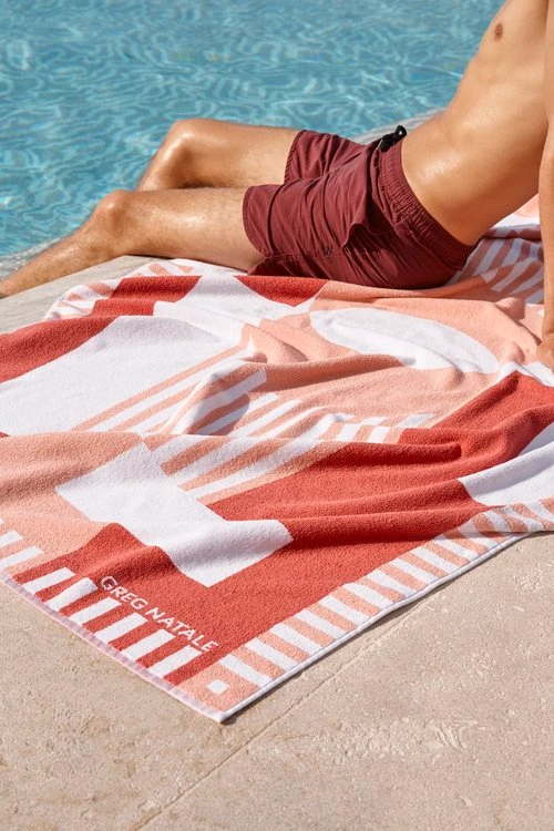 Man reclining on a patterned beach towel by an outdoor swimming pool in Melbourne styled by Vanessa Timmins.