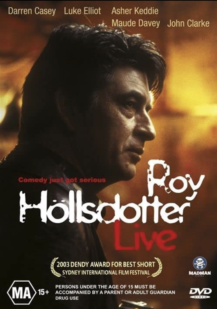 Movie poster featuring an adult man in a dark setting, with film credits at the top, 'Roy Hollsdotter Live' in a red font.