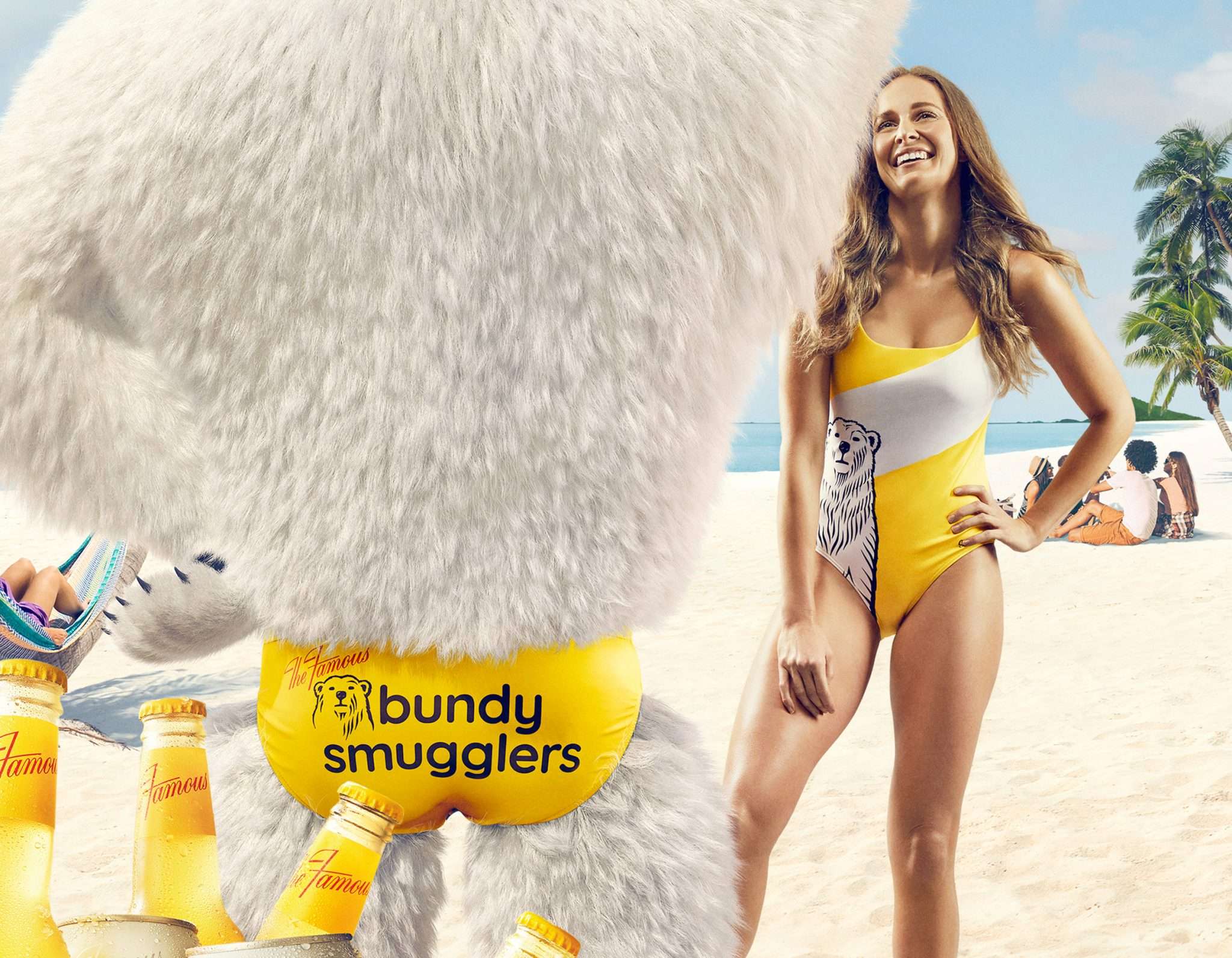 A woman in a swimsuit stands on a beach next to a person in a polar bear costume, with beer bottles on the sandy ground.
