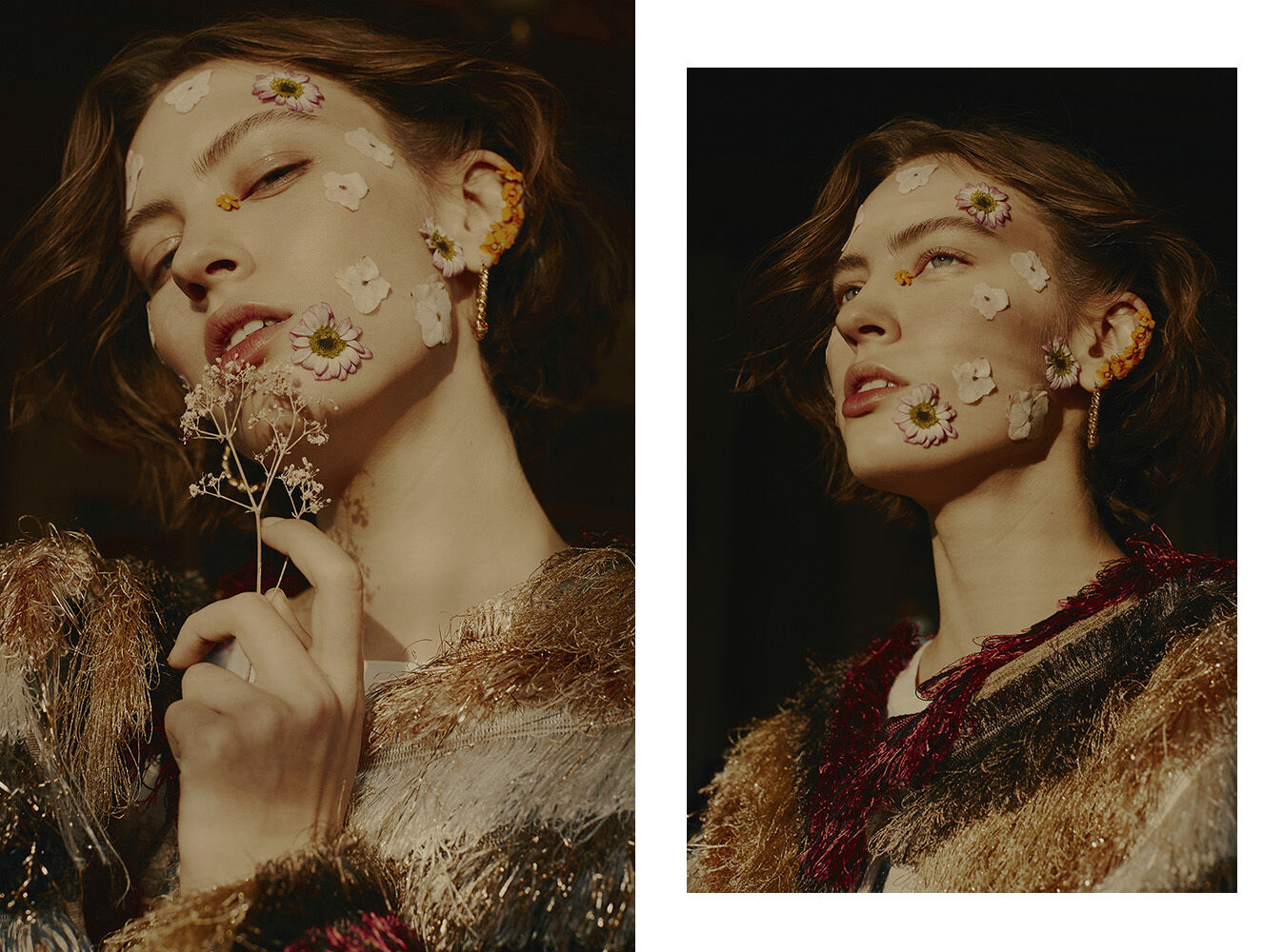 Portrait of a young woman with flowers on her face and in her hair, wearing a fringed jacket, shot in a dark, warm studio environment.