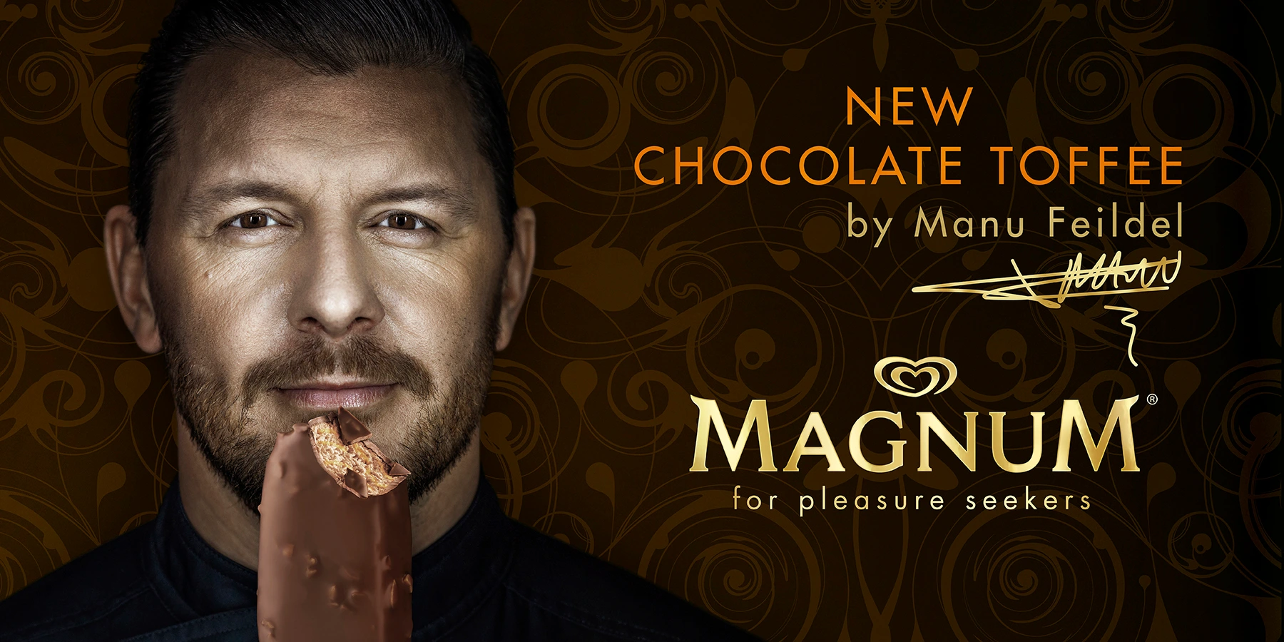 Close-up portrait of Manu Feildel holding a Magnum chocolate ice cream bar against a dark patterned background