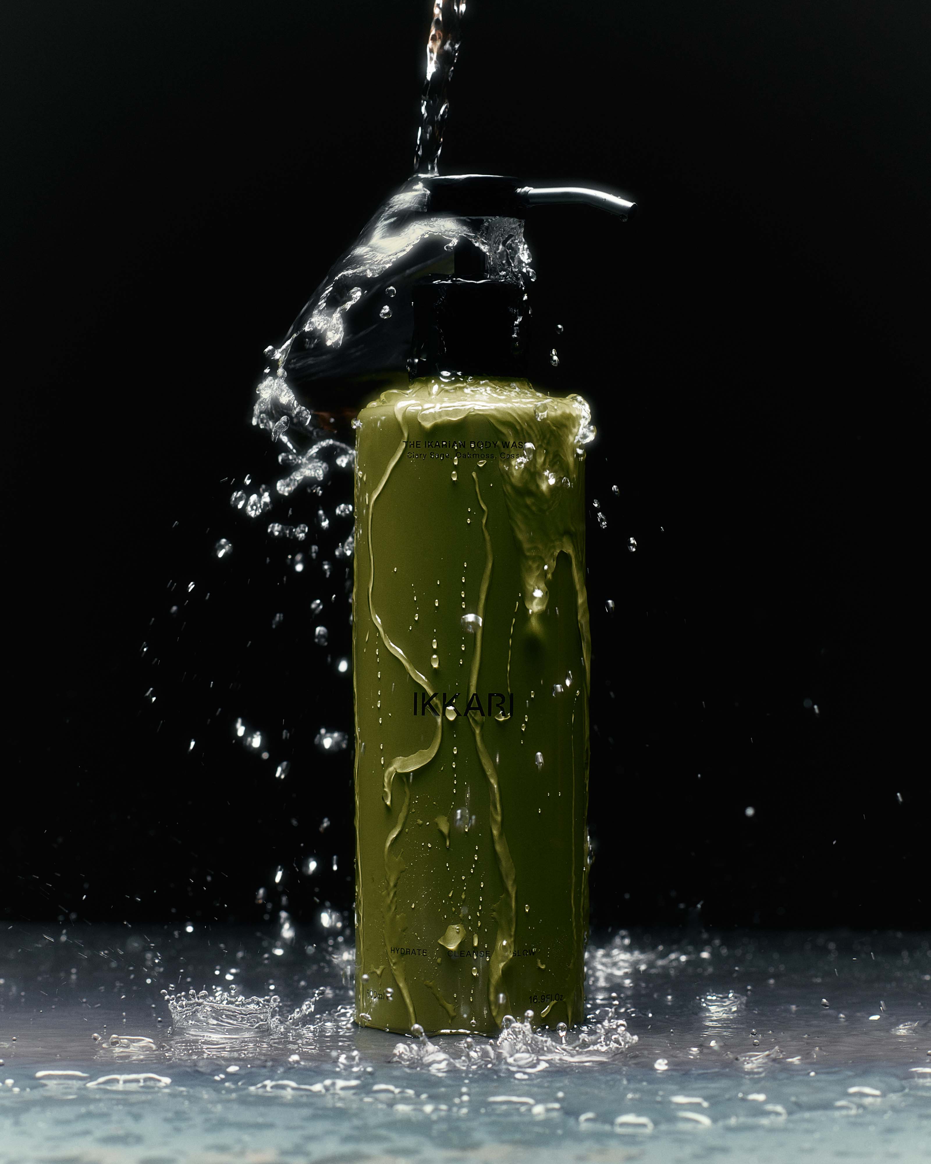 A product shot of a green pump bottle of shampoo being sprayed with water against a dark backdrop, creating splashes of water.