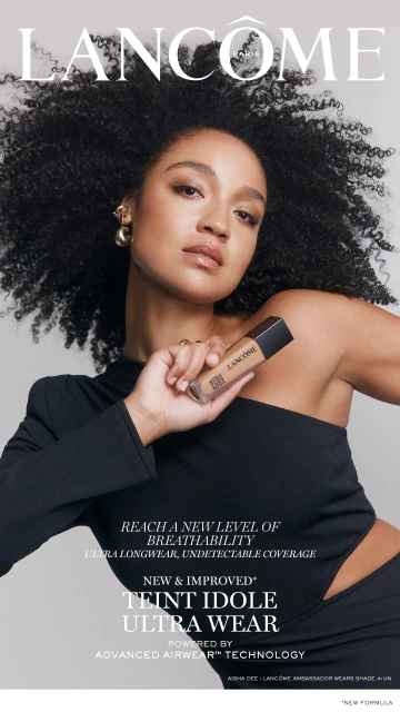 Cosmetics advertisement for Lancome featuring a woman with curly hair holding a bottle of Teint Idole Ultra Wear foundation.