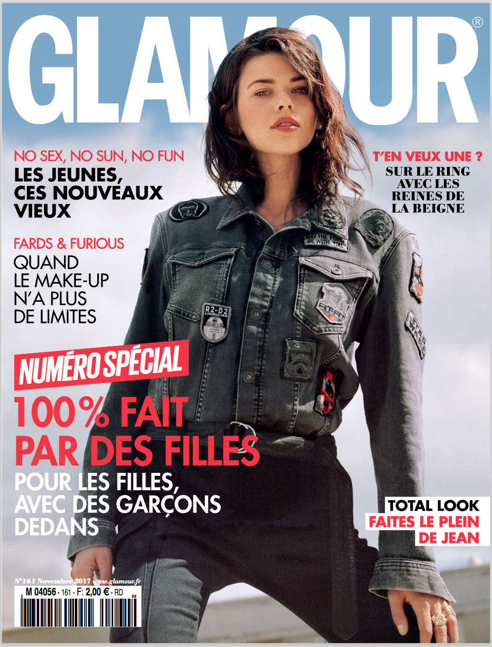 Glamour magazine cover featuring a young woman in a denim jacket and dark pants, with a sky-blue and white background, and various French headlines.