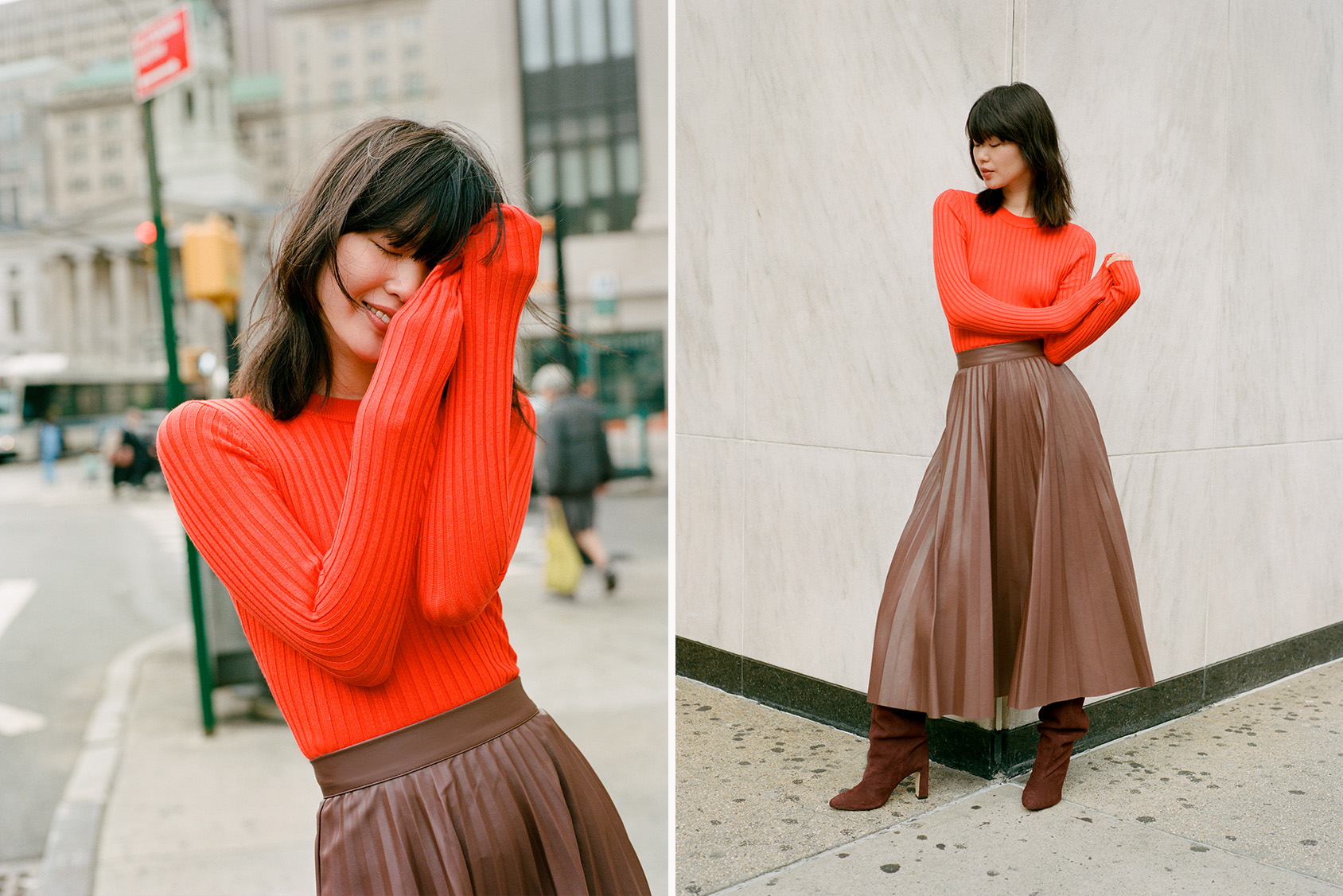 Woman in a vibrant red ribbed sweater and brown pleated skirt standing on a city street.