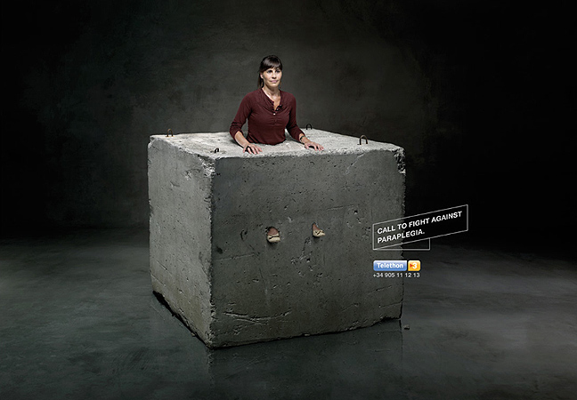 Woman encased in a concrete block, advertising campaign to raise awareness for paraplegia, indoors with dark background, conceptual.