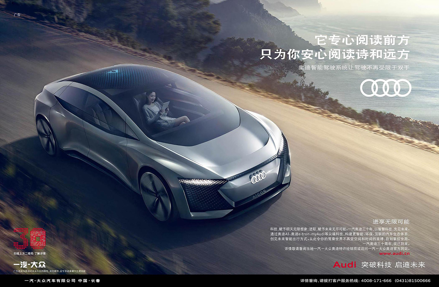 Silver Audi concept car on a winding road with a woman inside reading a tablet and a mountainous landscape in the background.