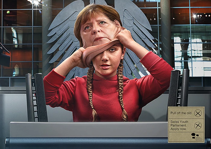Young woman in a red hoodie pulling off a realistic mask of an older politician against an institutional background.