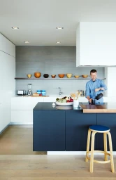 Man pouring water from a kettle into a cup in a modern kitchen photographed by Naomi Finlay in Melbourne.
