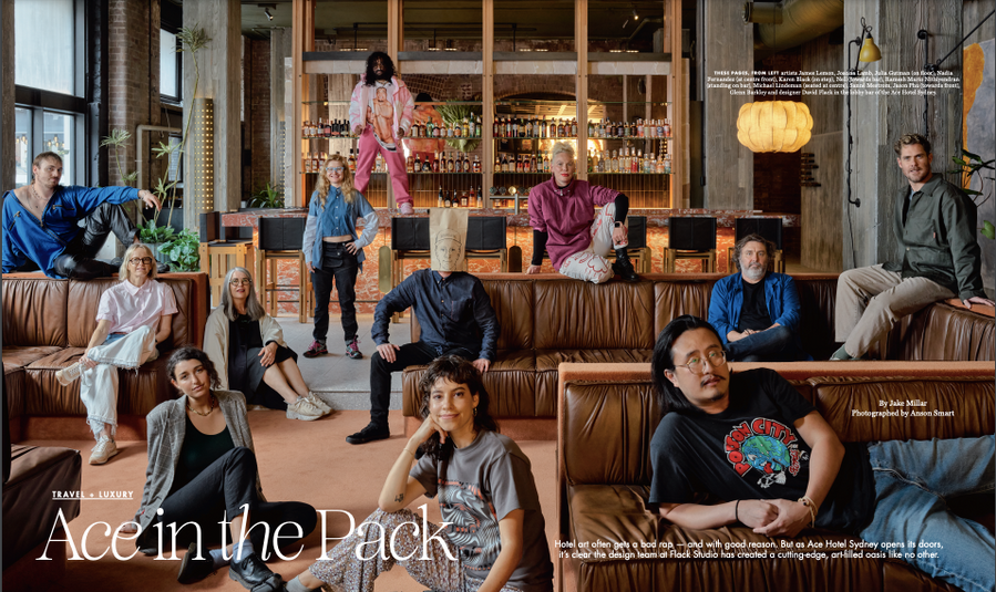 Group portrait of eleven adults posing on and around a brown leather couch in a hotel bar setting, indoor, daytime.