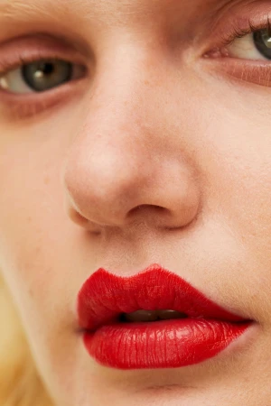 Extreme close-up macro beauty portrait of a woman wearing vivid red lipstick by make-up artist Lorella Giannini