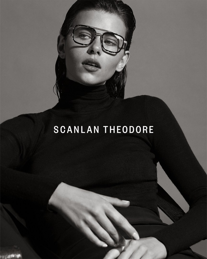 Model wearing dark tinted glasses and a black turtleneck sweater against a grey background photographed by Robbie Fimmano