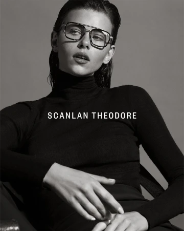 Model wearing dark tinted glasses and a black turtleneck sweater against a grey background photographed by Robbie Fimmano