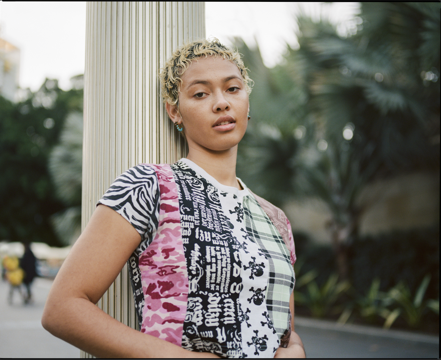 A woman with fair skin and blonde hair poses indoors wearing a black top and jeans, against a neutral backdrop.