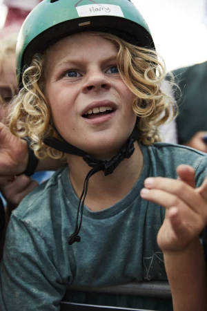 Young child with curly blonde hair wearing a green helmet labelled Harry and a blue t-shirt outdoors in Sydney