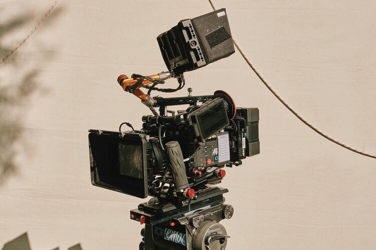 Professional film camera on a tripod with a light tan background for film or television production, offering crisp, high-resolution footage.
