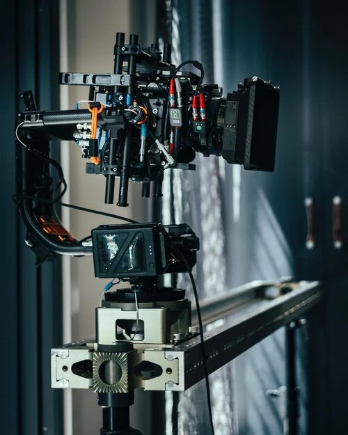 Professional broadcast camera on a track, indoors. Complex camera rig for video production with cables, monitor, and gear system.