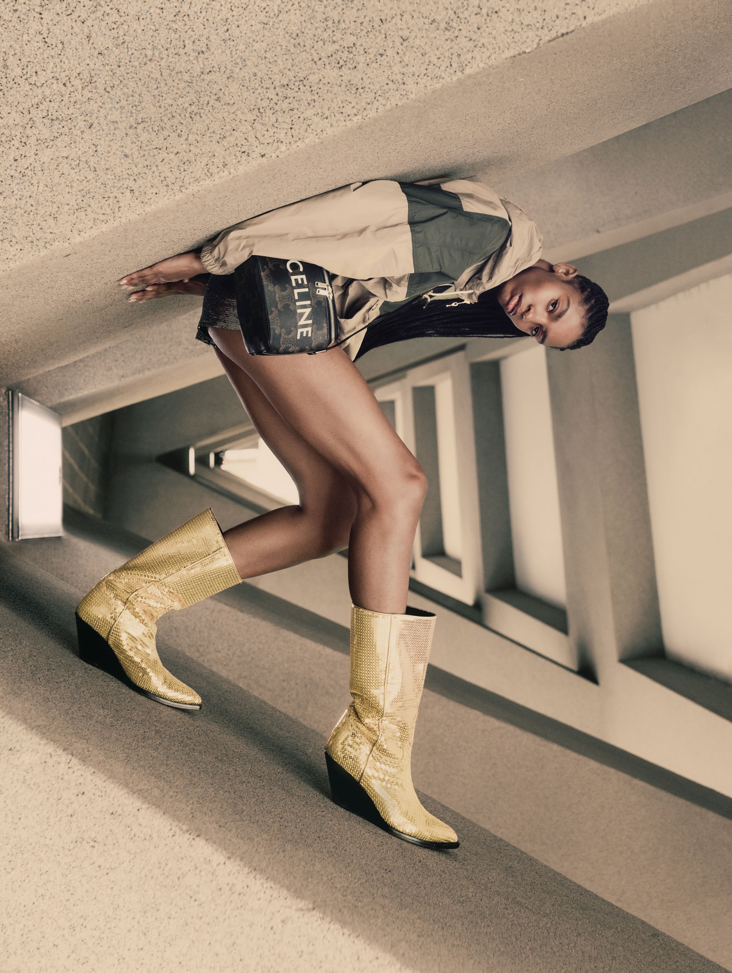 Woman poses on staircase wearing yellow cowboy boots, shorts, neutral jacket and black purse.  Fashion editorial photography.