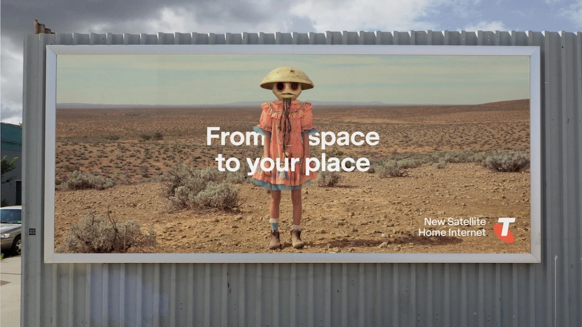 Billboard advertisement with a person in a costume standing in a desert landscape and the words 'From space to your place'.