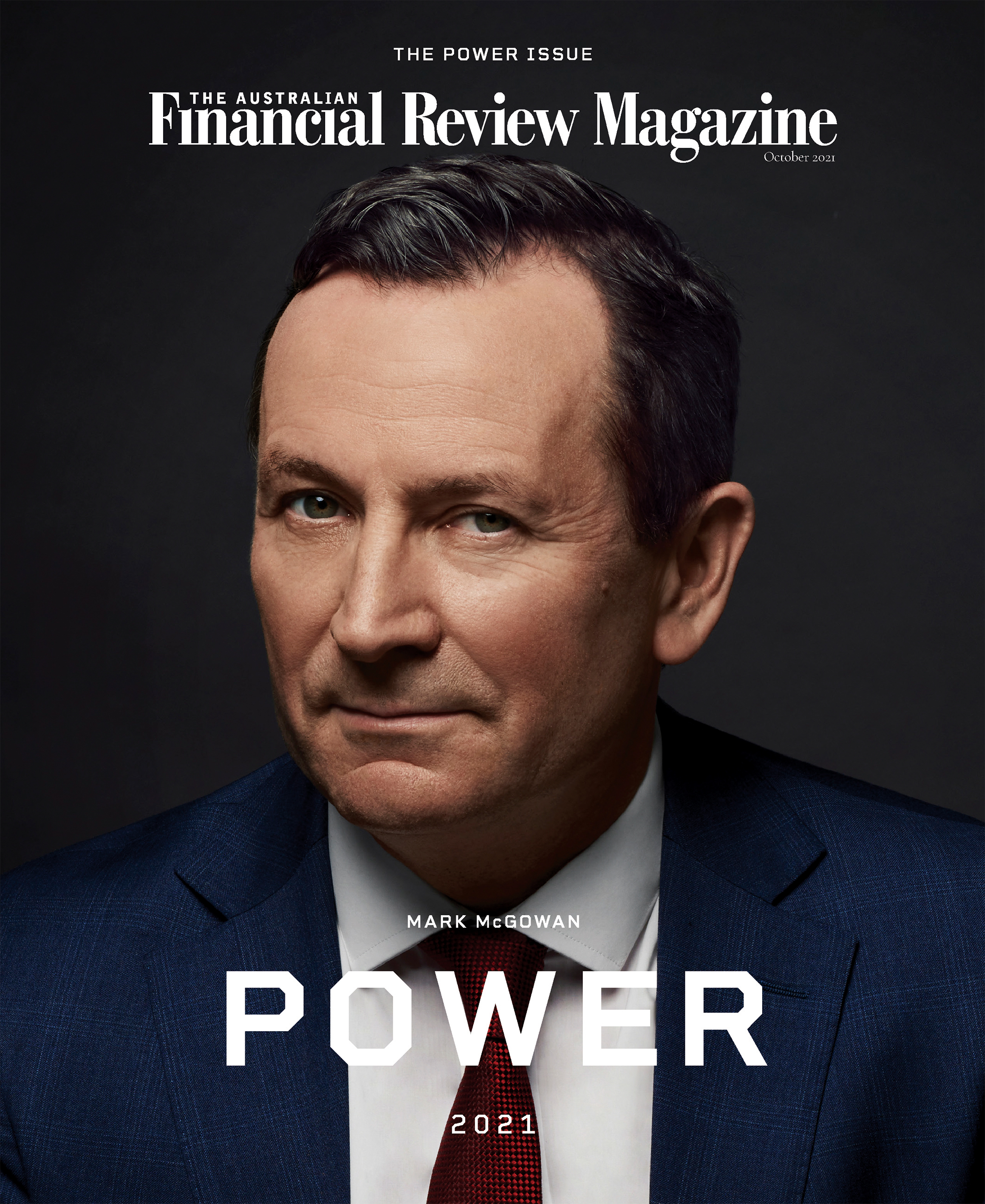 Portrait of Mark McGowan wearing a blue suit, white shirt, and red tie against a dark grey background.