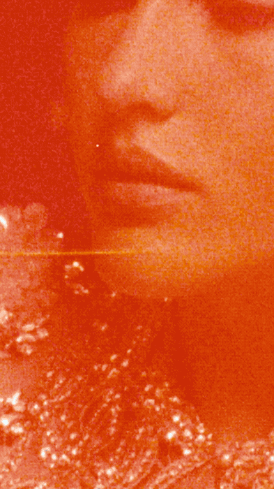 Close-up portrait of a woman with an orange color grade, highlighting her lips, and ornate details on her dress or top.
