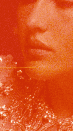 Close-up portrait of a woman with an orange color grade, highlighting her lips, and ornate details on her dress or top.