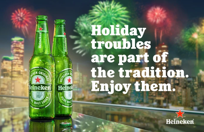 Two green Heineken beer bottles are prominently displayed against a backdrop of fireworks over a city skyline, promoting festive holidays.