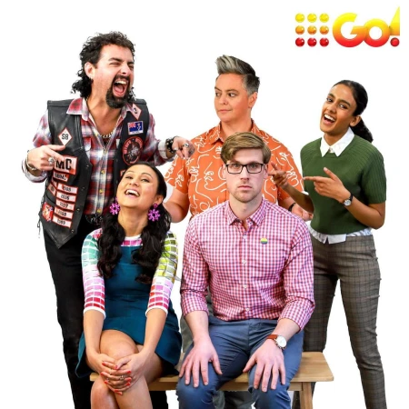 Group shot of five people in unique outfits posing on a white background. The people are on a wooden bench and smiling.