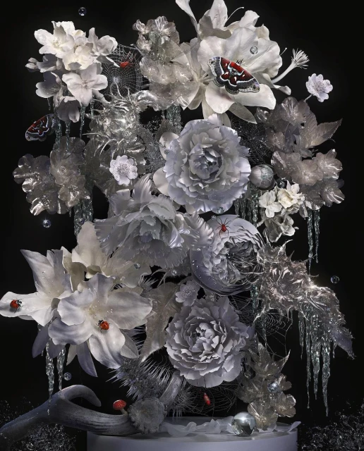 Floral arrangement with white orchids, peonies, silver foliage, butterflies, and ladybugs against a dark background, creating an elegant still life.