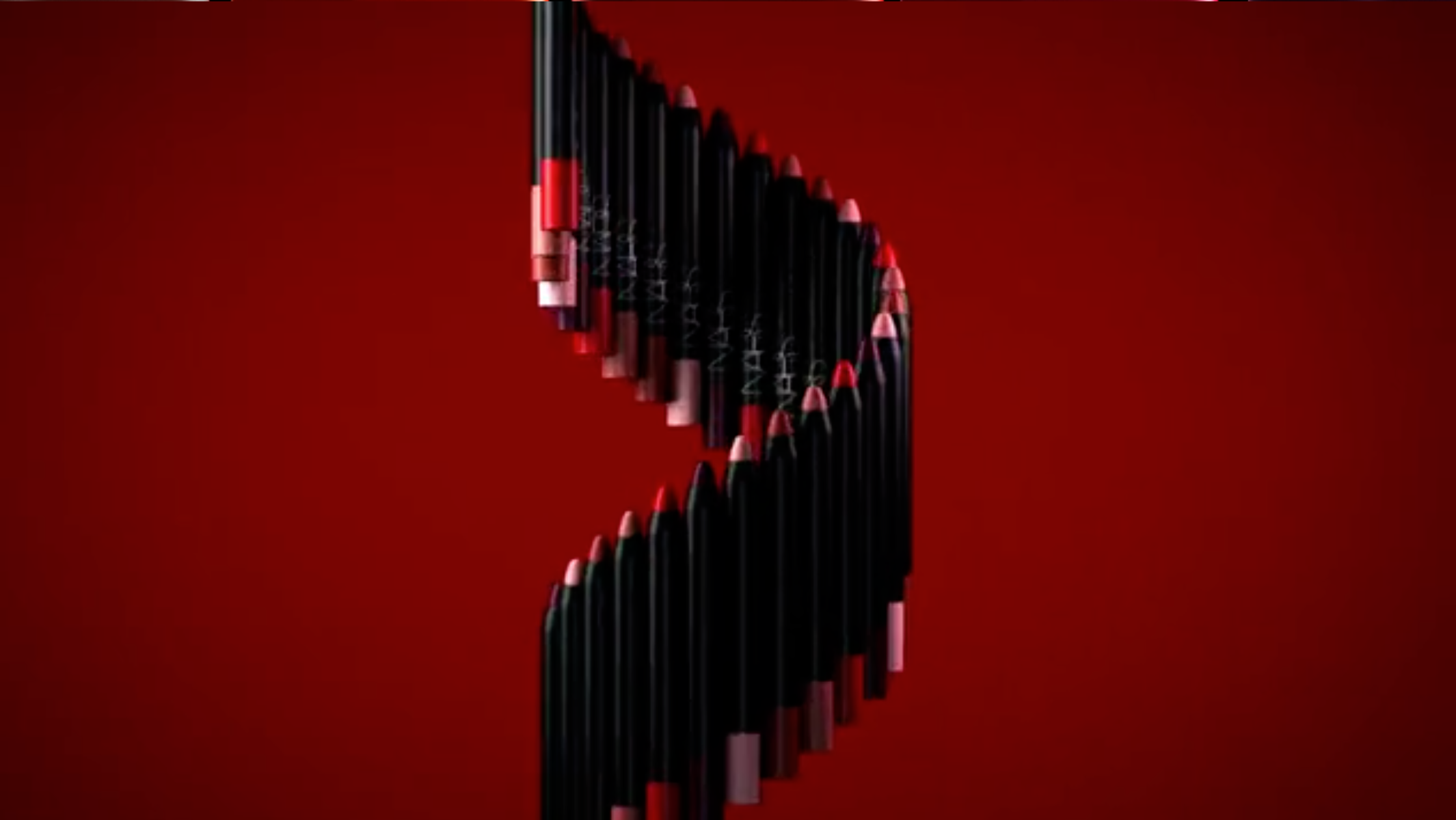 Arrangement of NARS lip pencils in a swirling line against a red backdrop, beauty product, cosmetics, lipstick, lip liner