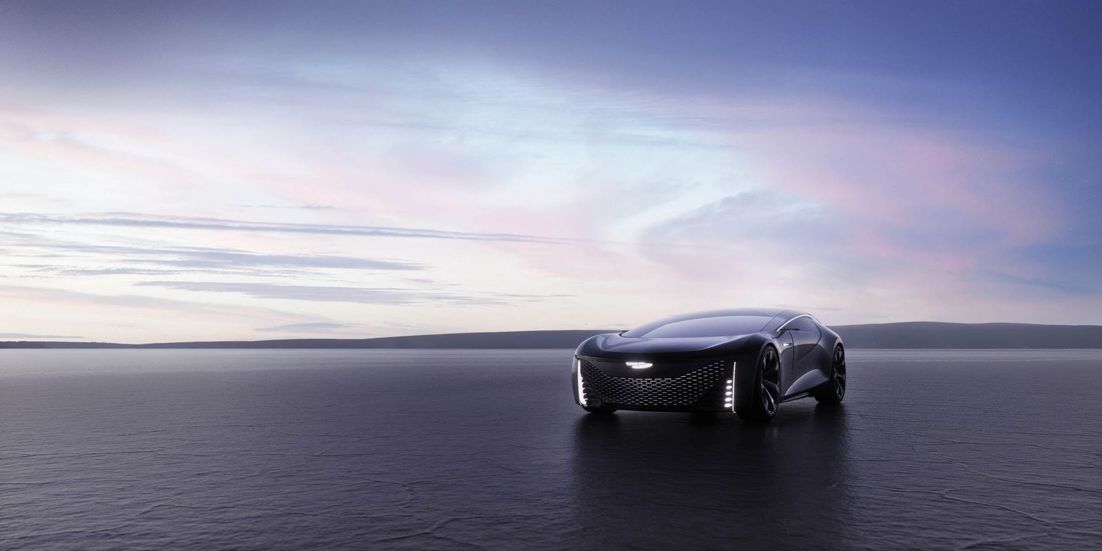 Sleek, black electric car on a flat plain with a distant body of water under a pastel sunset sky, showcasing automotive design.