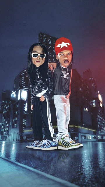 Two people stand side-by-side on a wet city street at night, showcasing Adidas apparel and accessories against an urban backdrop.