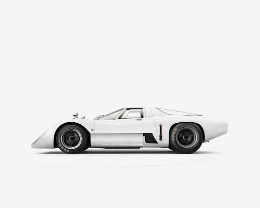 Side view of a white race car with black tires sitting on a white surface in a photo studio environment. Clean studio lighting.