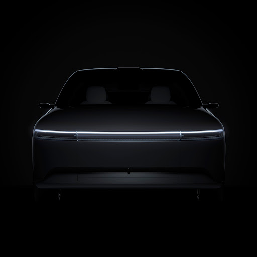 Sleek car design illuminated in darkness, showcasing a futuristic aesthetic with a glowing light bar and minimalist silhouette.