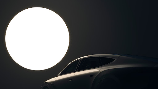 Sleek silver car in studio lighting with a large, bright circular light source in the background, creating a modern, automotive scene.