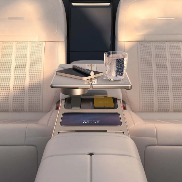 Car interior view: a table with a pen, notepad, and drink on leather seats offers luxury travel and automotive design.