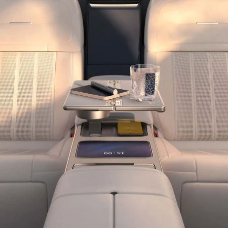 Car interior view: a table with a pen, notepad, and drink on leather seats offers luxury travel and automotive design.