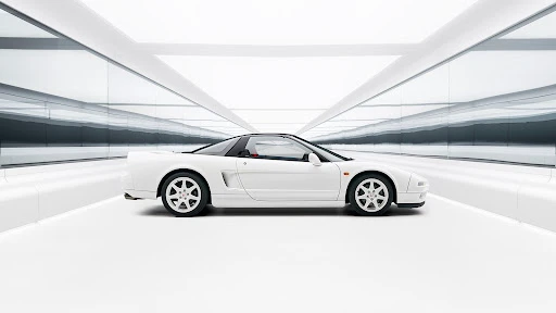 Side view of a white Honda NSX sports car parked inside a modern, minimalist garage featuring glossy white walls and floor.