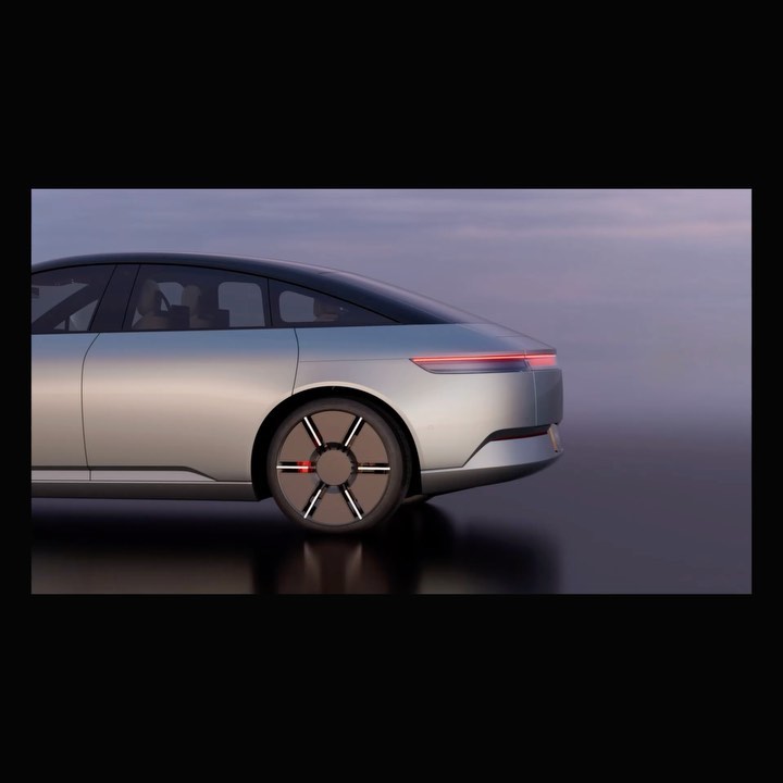 Sleek silver electric car design showcased in a studio setting with soft lighting highlighting its aerodynamic shape and unique wheel design.