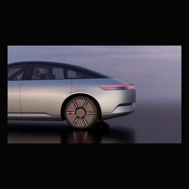 Sleek silver electric car design showcased in a studio setting with soft lighting highlighting its aerodynamic shape and unique wheel design.