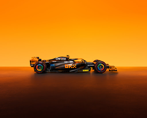 Formula 1 race car on display featuring a sleek design with orange and black accents, set against an orange gradient background.