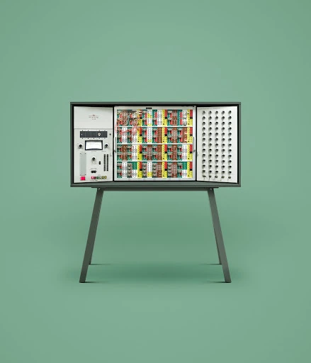 Vintage modular analog synthesizer set on a pale green background. The electronic instrument rests on a gray stand with splayed legs.