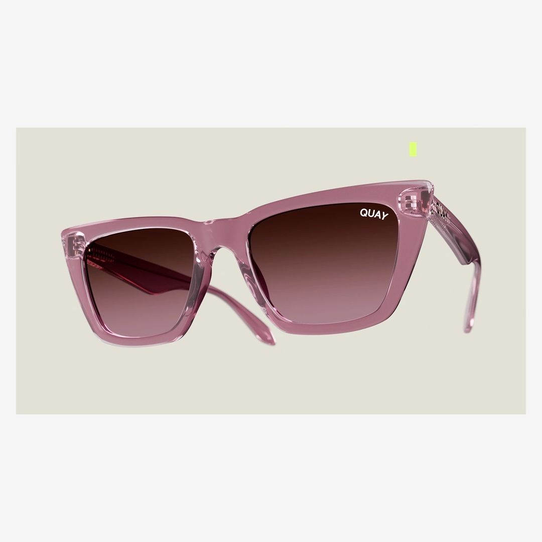 Pink Quay sunglasses with brown gradient lenses isolated against a light gray backdrop in a product-style studio shot.